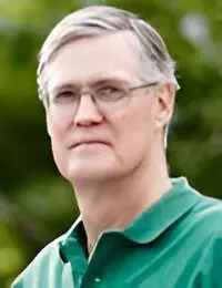 Man with glasses wearing a green polo shirt.