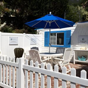 A white fence with chairs and an umbrella.